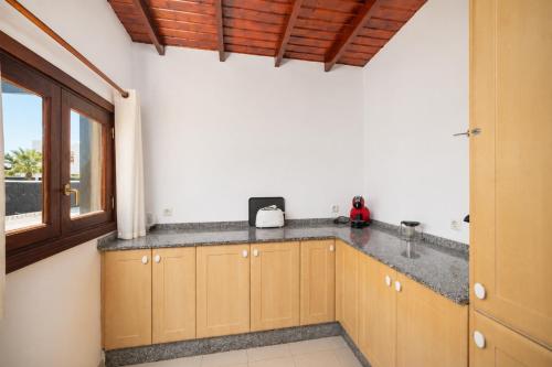 a kitchen with wooden cabinets and a counter top at Villa Alexsandra in Playa Blanca