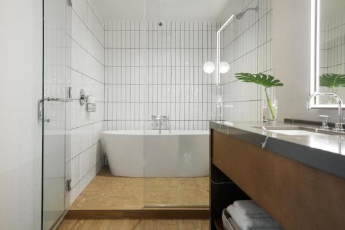 a white bathroom with a tub and a sink at Kimpton - Harper Hotel by IHG in Fort Worth