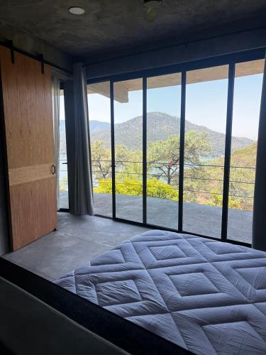 a bedroom with a large bed with a large window at Boutique Loft – Spectacular View – Lake – Mountain in Valle de Bravo
