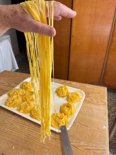 a person holding up noodles on a plate with a knife at Albergo Ristorante Lo Scoiattolo in Campigna