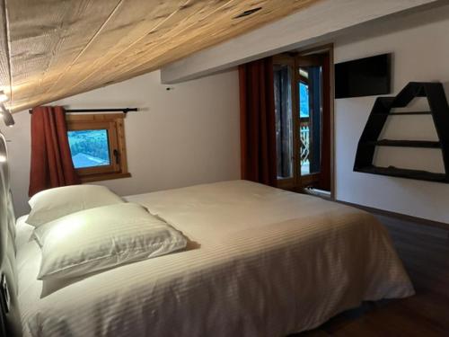 a bedroom with a white bed with two windows at Nid des aiguillettes in Chevenoz