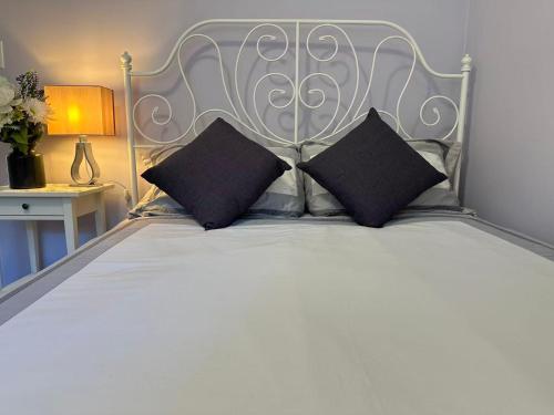 a white bed with two black pillows on it at Amazing Garden view unit in Toronto