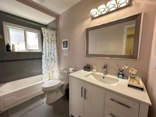 a bathroom with a sink and a toilet and a mirror at Amazing Garden view unit in Toronto