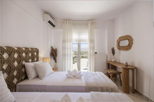 a white bedroom with a bed and a window at Casa Di Flora in Agios Prokopios