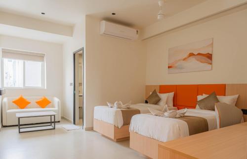 a hotel room with two beds and a couch at Casa Hotel Hitech City in Hyderabad