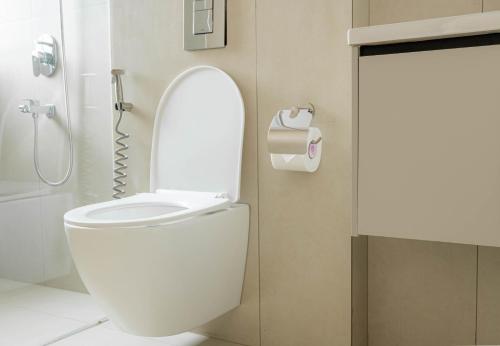 a bathroom with a toilet and a roll of toilet paper at Casa Hotel Hitech City in Hyderabad
