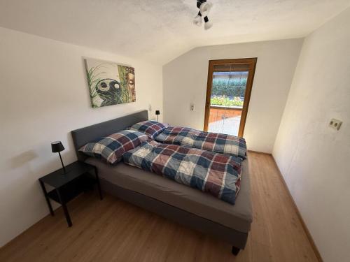 a bedroom with a bed with a plaid blanket and a window at Ferienwohnung Sonnheim Alpbachtal Card inklusive in Alpbach