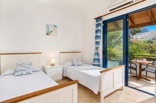 two beds in a room with a balcony at Villa Seashell in Pefki
