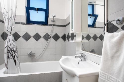a white bathroom with a sink and a bath tub at Villa Seashell in Pefki