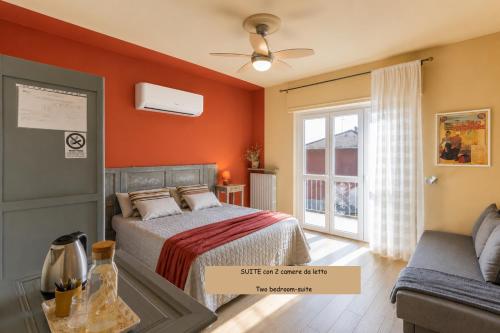 a bedroom with orange walls and a bed and a couch at B&B Tra i Laghi in Casale Corte Cerro