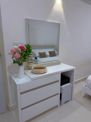 a bathroom with a white vanity with a mirror and flowers at Minique stay - spacious 3BR in Furena