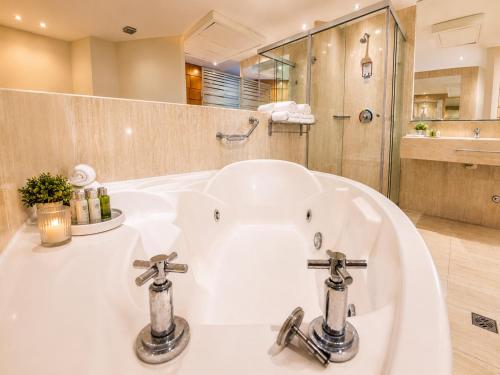 a bathroom with a bath tub with two faucets at Hotel Pascana Plaza in Santa Cruz de la Sierra