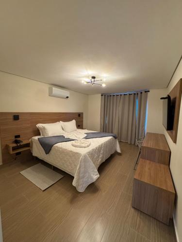 a bedroom with a large bed and a television at Le Bonne Ville Hotel in Campos do Jordão