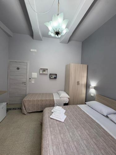 a bedroom with two beds and a chandelier at Scilla Central Rooms in Scilla