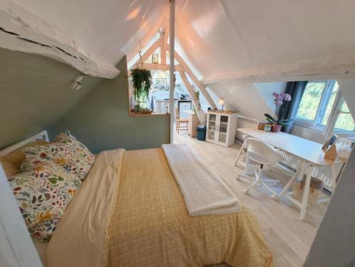 a bedroom with a bed and a desk in a attic at Quiet Riverside Apartment in Grosley-sur-Risle
