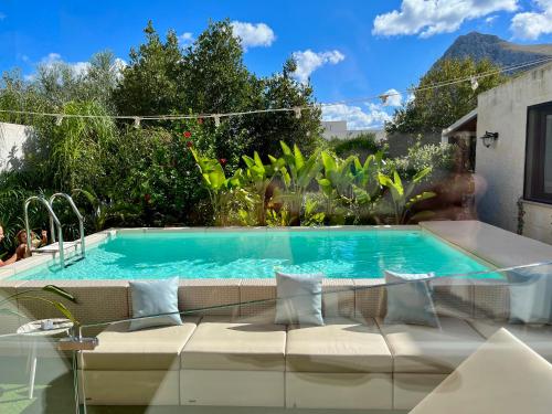 a swimming pool with a couch in front of a house at Ricordi Siciliani - Charme Rooms in San Vito lo Capo