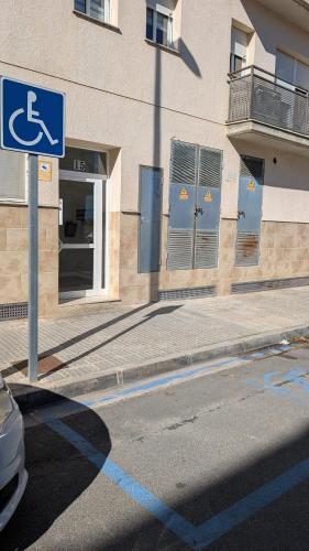a street sign in front of a building with a handicapped sign at Somnis del Delta, Apartamento Deltebre, Delta Ebro in Deltebre