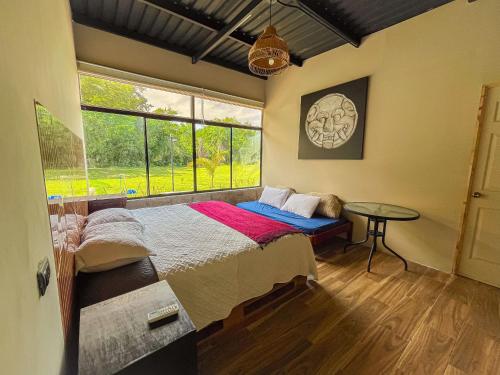 a bedroom with a bed and a table and a window at Suite Quelepa San Miguel in Quelepa