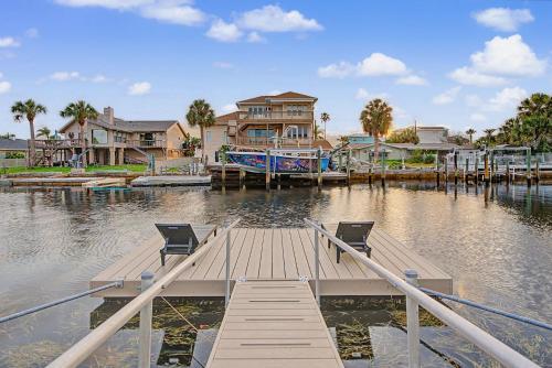 a dock with two chairs and a house on the water at Moonlight Bay in Port Richey