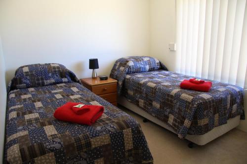 two beds in a room with red pillows on them at Byford House on the Scarp in Armadale