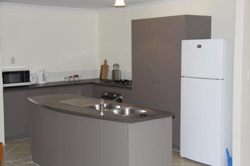 a kitchen with a sink and a white refrigerator at Byford House on the Scarp in Armadale