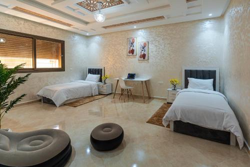 a bedroom with two beds and a table and a desk at Sahoria Stay in Dakhla