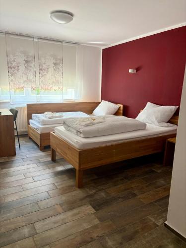 two beds in a room with a red wall at Franz - Josef in Emmingen-Liptingen