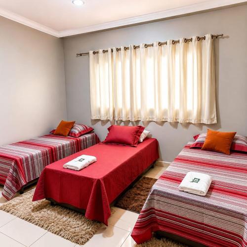 two beds in a room with red sheets at Pousada Bem Estar Frutal in Frutal