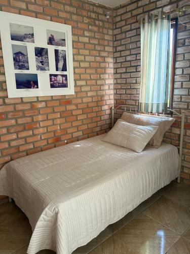 a bed in a room with a brick wall at Estação Serrana in Pedro II