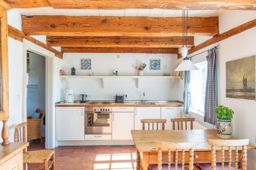 a kitchen with white cabinets and a wooden table at Ferienwohnung Schulkate I - Boldevitzer Rügenkaten in Parchtitz