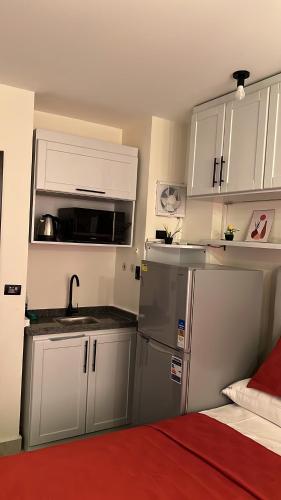 a kitchen with white cabinets and a sink and a refrigerator at Zahra Elegant Studio in Sīdī ‘Abd ar Raḩmān