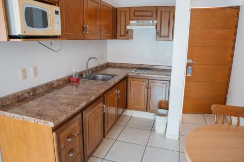 a kitchen with wooden cabinets and a sink and a microwave at Hotel La Joya Del Lago in Ajijic