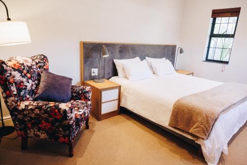 a bedroom with a bed and a chair at Suite 273 - Luxe Solar Suite - Heated Pool in Cape Town