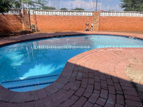 a large swimming pool with a brick wall at 4bnb in Gaborone