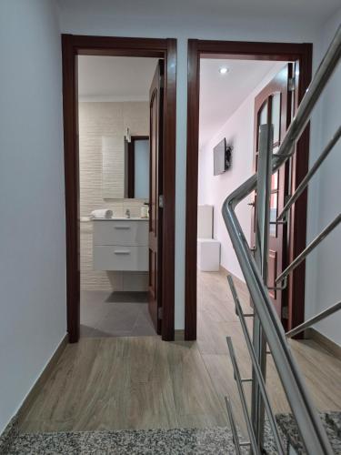 a hallway with a bathroom with a sink and a mirror at Casa Beleví - Laxe, sea and rest in Laxe