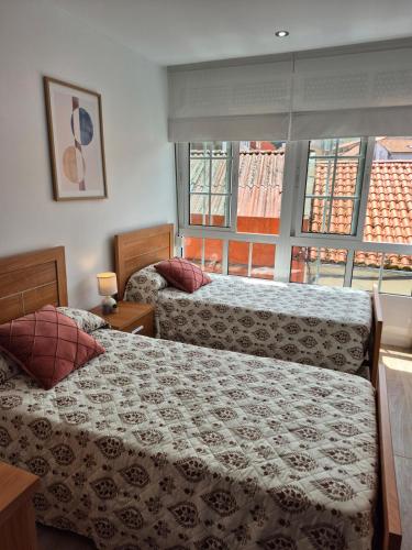 a bedroom with two beds and a large window at Casa Beleví - Laxe, sea and rest in Laxe