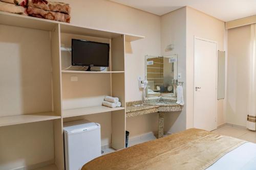 a room with a bathroom with a television and a sink at Pousada Cataratas in Foz do Iguaçu