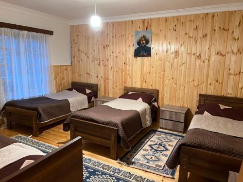 three beds in a room with wooden walls at Gudani Temi in Gudani