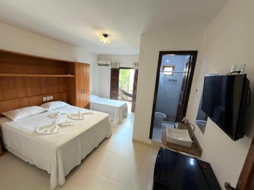 a bedroom with a bed and a flat screen tv at Pousada Coqueiro do Caitá in Morro de São Paulo