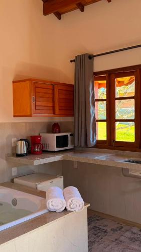 a kitchen with a bath tub and a microwave at Apartamentos da Jo in Monte Verde