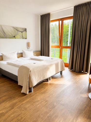 a bedroom with a large bed and a large window at Sporthotel Fuchsbachtal in Barsinghausen