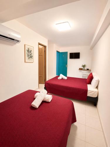 two beds in a hotel room with red sheets at Pacific Coast Hotel in Playa Bonita Village