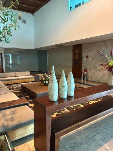 four white vases sitting on a table in a lobby at Flat com vista para o mar - apto 1605 in Natal