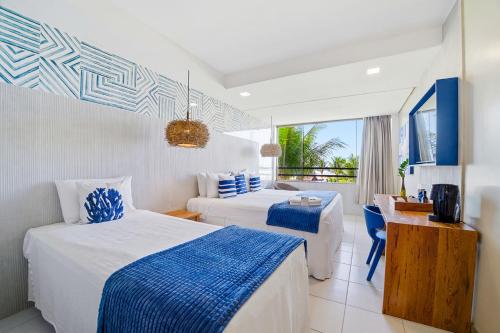 a hotel room with two beds and a balcony at Hotel Praia do Sol in Ilhéus