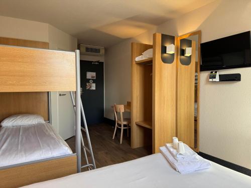 a small room with a bed and a bedroom with a tv at B&B HOTEL Auxerre Monéteau in Monéteau