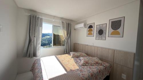 a small bedroom with a bed and a window at Apto Rosas| 3Q, todo Climatizado, Prox das Termas in Piratuba
