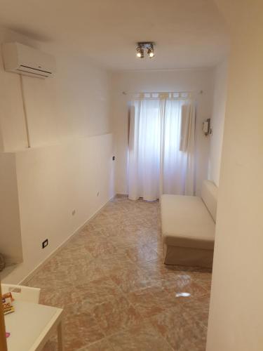 Cette chambre blanche dispose d'un canapé et d'une fenêtre. dans l'établissement Peri Peri Holiday Home Catania, à Catane