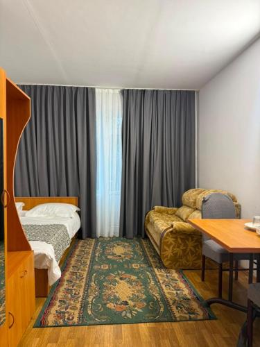 a hotel room with a bed and a desk and a table at Barskhan Guest House in Bosteri