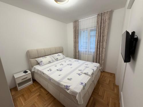 a small bedroom with a bed and a television at Stan na dan Hilandarska 9 in Lukavica