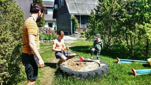 a man and two boys playing in a sandbox in a yard at Kuivastujaani in Kuivastu